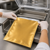 Medewerker plaatst een goud-zilveren vacuümzak in een professionele vacuümmachine.