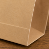 Close-up van de hoek van een bruin FSC papieren hamburgerzakje. De detailfoto toont de strakke vouwlijnen, stevige afwerking en natuurlijke kraftpapierstructuur van het zakje.
