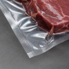Close-up detailfoto van een transparante krimpzak met bodemseal in gebruik, strak om vlees gevacumeerd, waarbij de sterke sealing, heldere folie en luchtdichte verpakking duidelijk zichtbaar zijn.