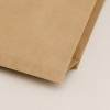 Detailopname van de hoek van een bruin papieren hamburgerzakje van kraftpapier. De close-up laat de stevige vouwconstructie, nette afwerking en natuurlijke papierstructuur zien.