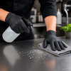 Zwarte nitril handschoenen maat M in gebruik tijdens het reinigen en desinfecteren van een RVS werkblad, ideaal voor hygiënische schoonmaakwerkzaamheden in de horeca, voedingsindustrie en professionele keukens.