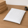 Witte LDPE verzendzak volledig gesloten en gevuld, geplaatst op een werktafel, ter illustratie van een veilig verpakte zending klaar voor verzending.
