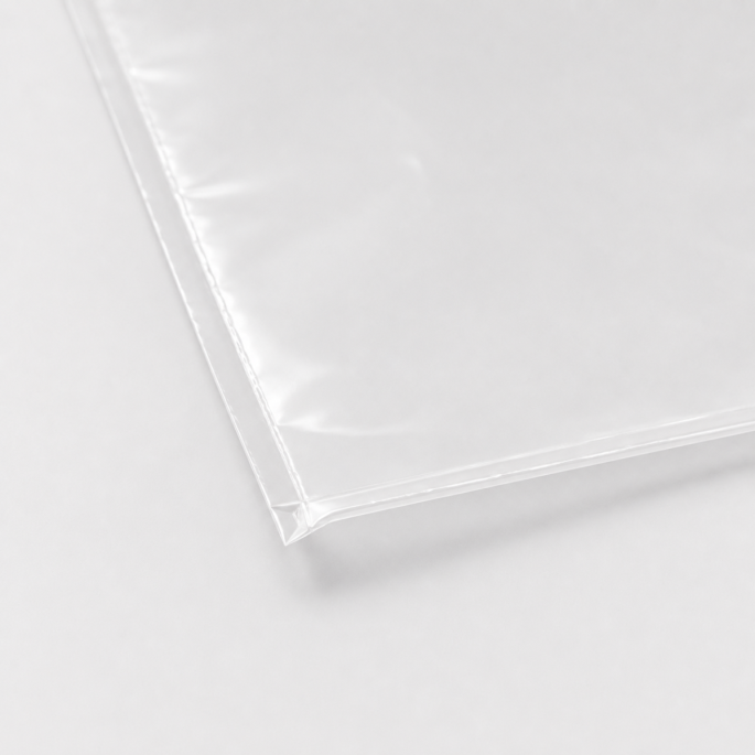 Ingezoomde detailfoto van de afgesloten onderhoek van een transparante gladde vacuümzak van 400 × 700 mm, waarbij de rechte lasnaad, zijnaad en dunne folie duidelijk zichtbaar zijn tegen een lichtgrijze achtergrond.