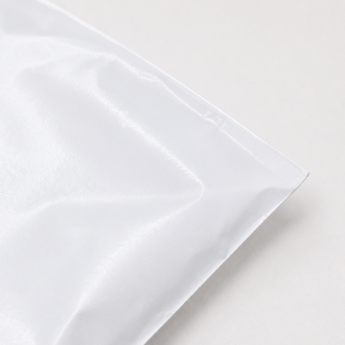 Close-up detailfoto van de rechterbovenhoek van een witte LDPE verzendzak, waarbij de glanzende textuur, stevige afwerking en subtiele vouwen van het kunststofmateriaal zichtbaar zijn.